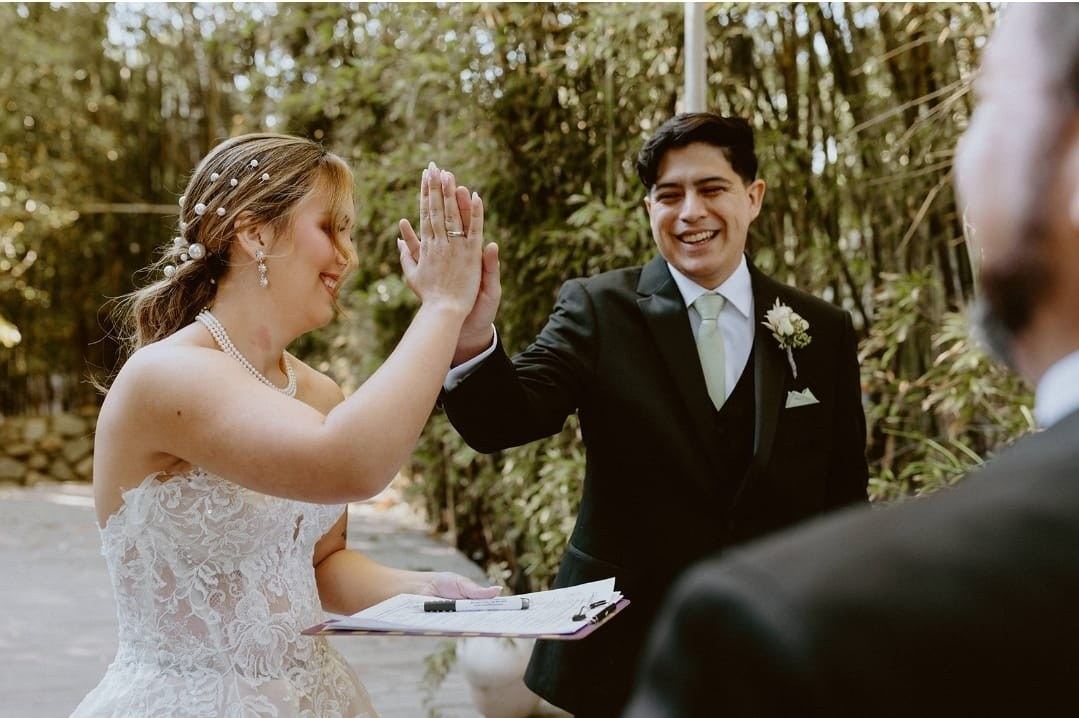 A bride and groom high-fiving each other moments after their marriage license is signed